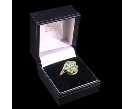 A peridot cluster ring comprising thirteen oval and round-cut stones, gallery twist-set between the open shoulders of a 9 ct 
