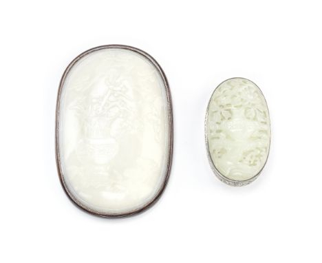 TWO JADE OVAL PLAQUES18th/19th centuryThe larger white jade plaque finely carved to depict a hu vase filled flowering prunus 