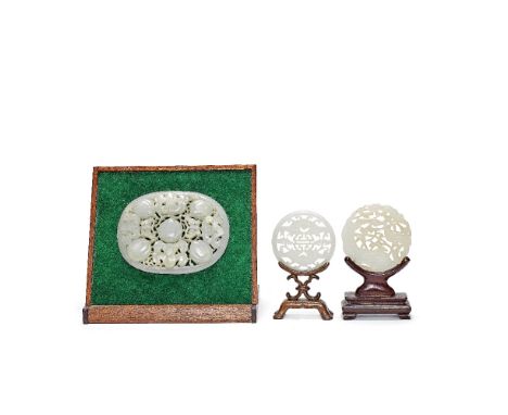 THREE PALE GREEN JADE PLAQUES19th centuryComprising: a pale green jade openwork roundel with bird and flowers, rosewood stand