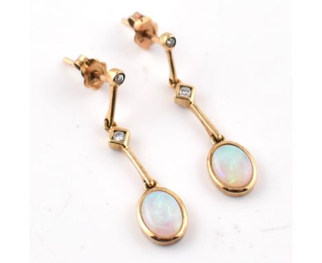 A pair of hallmarked 9ct gold, opal and diamond pendant earrings. The 9ct yellow gold earrings having a bezel set oval opal c