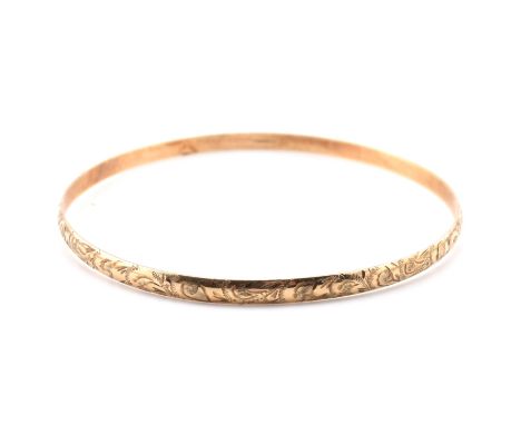 A hallmarked 9ct gold engraved bangle. The bangle having an all-over bright cut foliate engraved decoration. Hallmarked for L