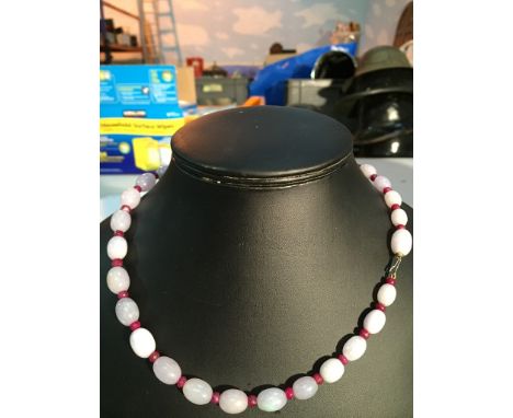 A white jade bead necklace with faceted rubies between beads on an 18ct clasp