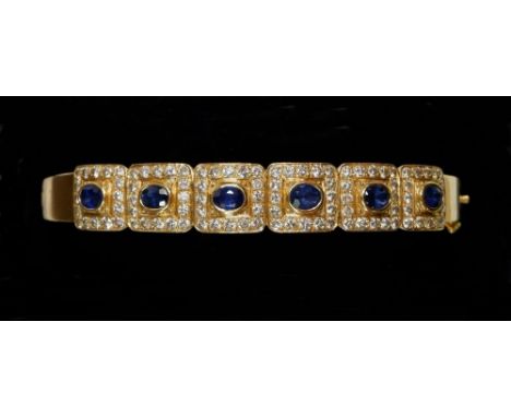 An 18 carat gold hinged bangle with six square panels set sapphires within diamond surround, total weight 25.3g 