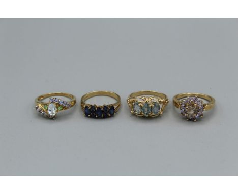 Four gem set 9ct gold dress rings. Featuring a sapphire set half hoop ring, size N, approximate weight 2.7 grams; a smoky qua