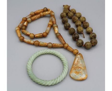 A selection of carved jade-type jewellery featuring a carved bracelet in nephrite jade, a carved bead necklace with yellow me