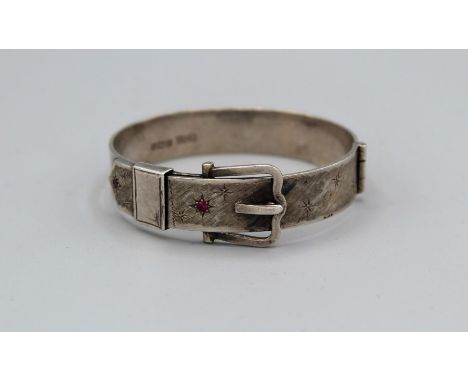 An Elizabeth II silver buckle form bangle, set with ruby coloured stones, Birmingham 1962