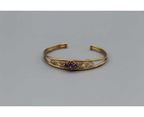 A 9ct gold openwork bangle, set oval and round cut amethysts, the principle stone approximately 5 x 3mm, 6gm