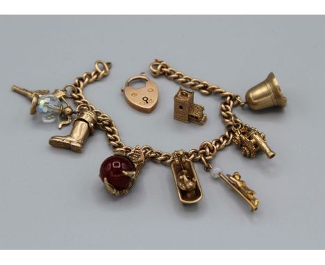 A 9ct gold charm bracelet, featuring a heart shaped padlock clasp and nine charms. The charms include a claw holding a carnel