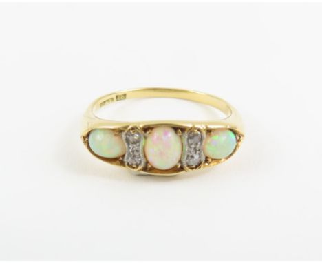 An early 20th century opal and diamond ring, the three oval cabochon cut opals with single cut diamond accents between, marke