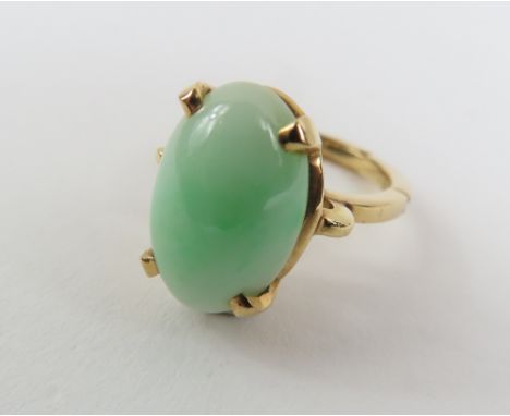 A single stone jade ring, the oval cabochon cut stone approximately 16.1mm x 10.45mm, with a band which is partially hinged, 