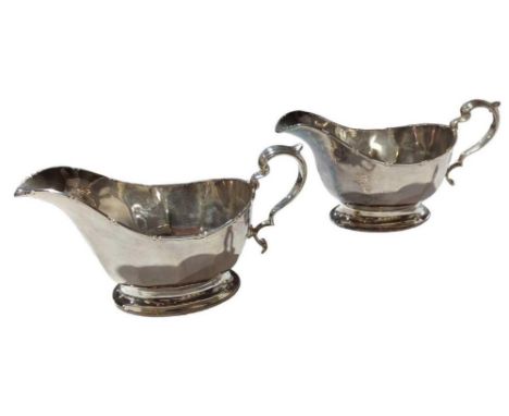 A pair of silver sauce boats, by Mappin & Webb, Birmingham, 1939, oval form with capped scroll handles and raised on an oval 