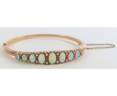 A Victorian opal and diamond hinged bangle, the nine oval cabochon cut opals with rose cut diamond accents between them, inte