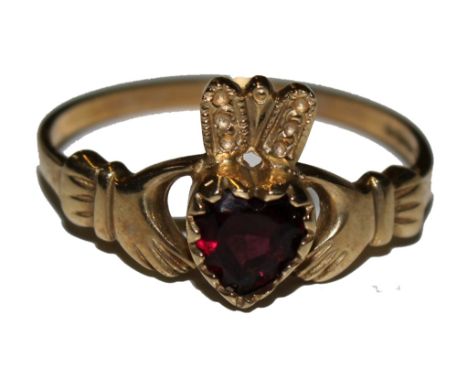 A 9 carat gold ring of two hands holding a heart shaped garnet