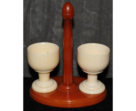 A pair of ivory egg cups on a catalin stand, 14cm  The Art Deco Carvings of W. G. Collins (1872-1959) Worshipful Company of T