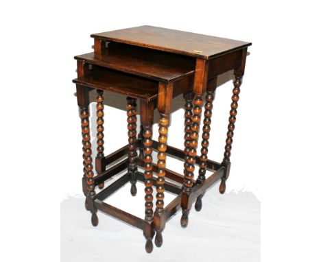 An early 20th century oak stained nest of three oblong tables with bobbin shaped legs and stretcher supports, 59H x 42W x 30c