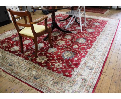 A Middle Eastern-style red-ground drawing room carpet with floral and foliate depictions with a double ivory border and long 