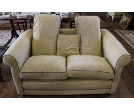 A contemporary fabric upholstered two seat sofa in cream, suedette, with removable cushions, shaped armrests on square block 