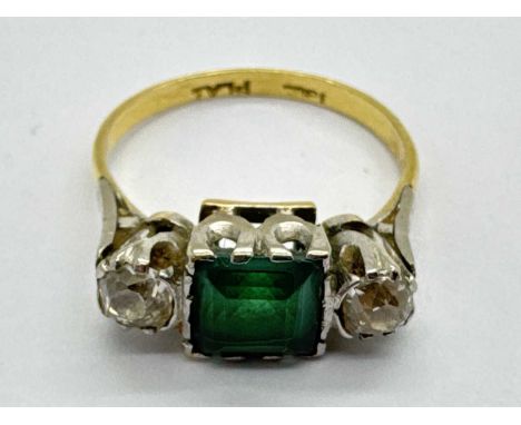 A Vintage Emerald and Diamond Three Stone Ring, the square cut centre stone collet set between circular brilliant cut diamond