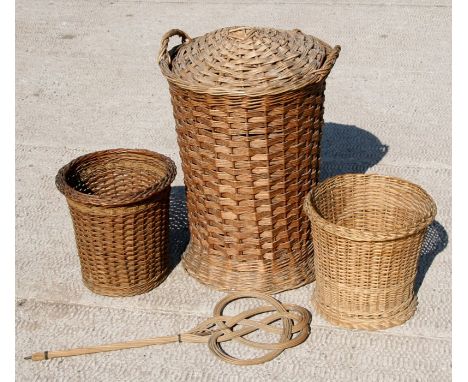 A wickerwork laundry basket, 66cms (26ins) high; together with two wastepaper baskets and a vintage carpet beater (4).