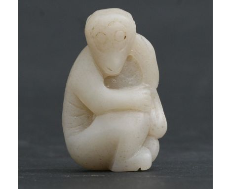 A Chinese mutton fat white jade figure carved in the form of a seated monkey, 5cms (2ins) high.