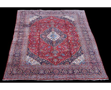 A Persian Kashan woollen hand knotted carpet with central floral medallion within floral borders, on a red and blue ground, 3