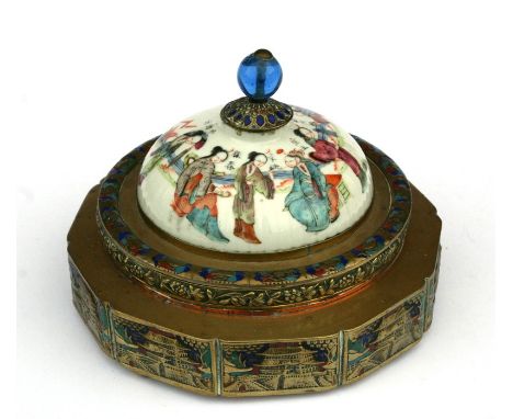 A Chinese circular brass and enamel lidded box decorated with pagodas within panels, the ceramic cover decorated with figures