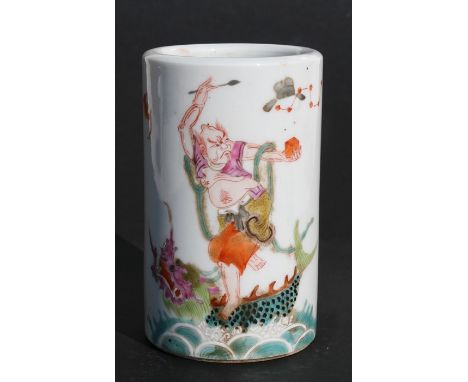 A Chinese famille rose brush pot decorated a figure standing on a mythical sea beast with calligraphy to the back and having 