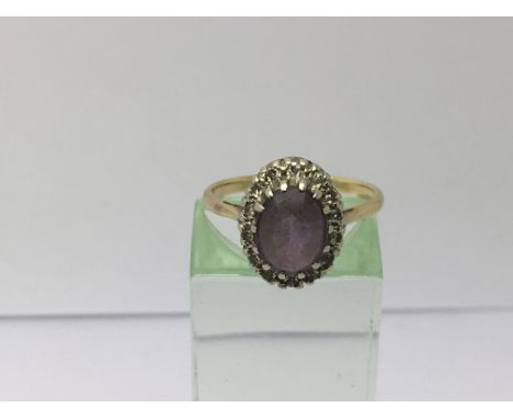 A gold ring set with an amethyst surrounded by diamonds, approx 3.3g and approx size L-M.