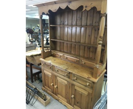 A pine dresser with a raised back and pillar supports above drawers and cupboards 137x48cm