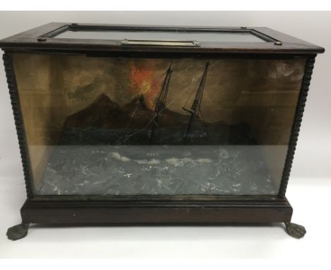 A glass cased Victorian music box automaton of a rocking sailing ship with a backdrop depicting an erupting volcano (Vesuvius