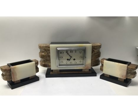 A marble Art Deco clock and side garnitures, with key and pendulum seen working.