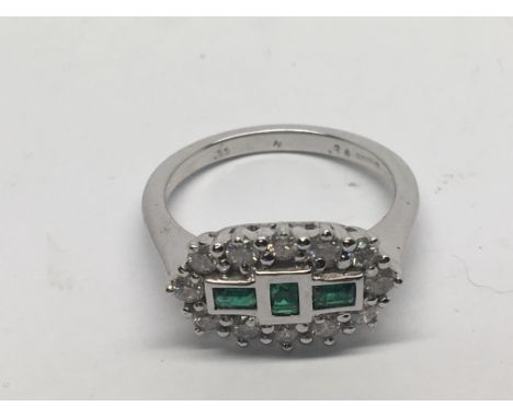 An 18carat white gold ring set with three Emeralds and a pattern of brilliant cut diamonds. Ring size M-N