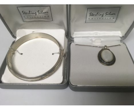A silver bangle and a silver pendant on chain .