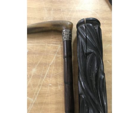 A carved walking stick and a walking cane with silver collar and horn handle .