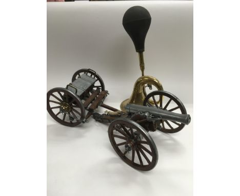 A model metal and wood cannon and a vintage car horn.