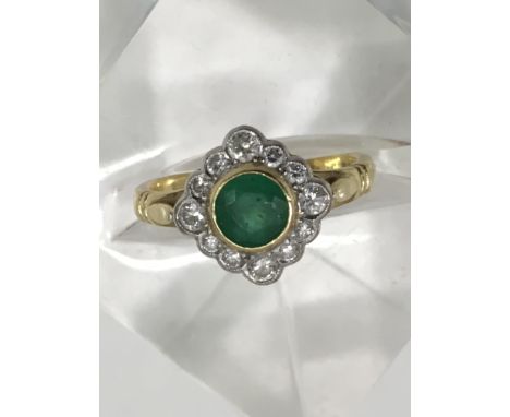 An 18ct gold ring set with central emerald in diamond surround.Approx M