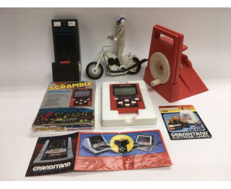 Two vintage hand held computer games and an Evil Knievel toy.
