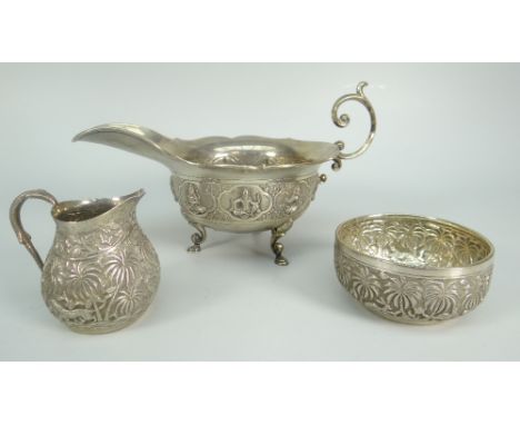 THREE PIECES OF BELIEVED INDIAN SILVER comprising scroll-handled sauce boat decorated with deities raised on scroll and pad f