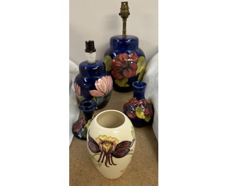 A Moorcroft table lamp decorated with flowers and leaves together with a smaller example, a candlestick and two vases 