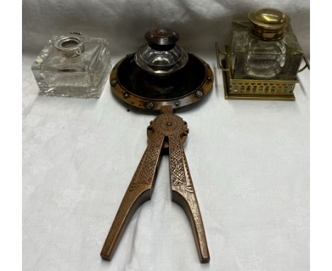 A brass and glass desk inkwell together with two other inkwells and a treen nut cracker 