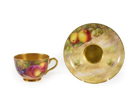 A Royal Worcester Porcelain Teacup and Saucer, 1952/53, painted with still lives of fruit on a mossy bank within gilt borders
