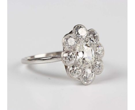 A diamond cluster ring in a flowerhead shaped design, mounted with the principal old cut diamond within a surround of eight c