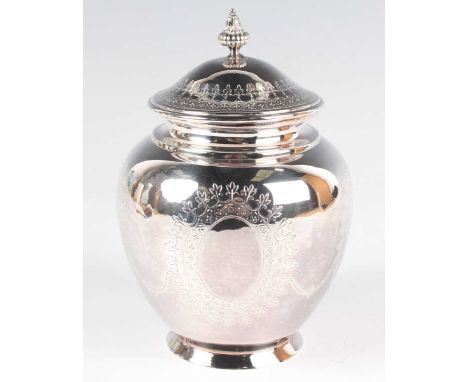 A George V silver tea caddy of ovoid form with domed hinged lid and knop finial, engraved with oval floral vignettes, on a ci