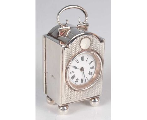 A George V silver bedside carriage timepiece of rectangular form with arched top and scroll handle, above a circular dial wit