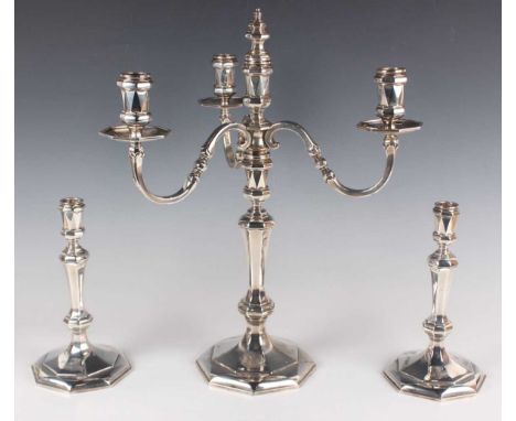 A George VI silver four-light three-scroll branch candelabrum and a pair of matching candlesticks, each of faceted octagonal 