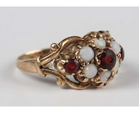 A gold, garnet and opal cluster ring, mounted with three garnets and six opals between scroll pierced shoulders, weight 2.9g,