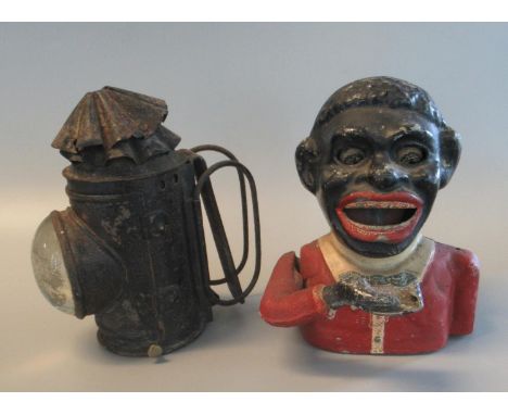 Cast metal novelty black man money box, together with a metal handheld probably policeman's oil lamp with bullseye lens. (2)(