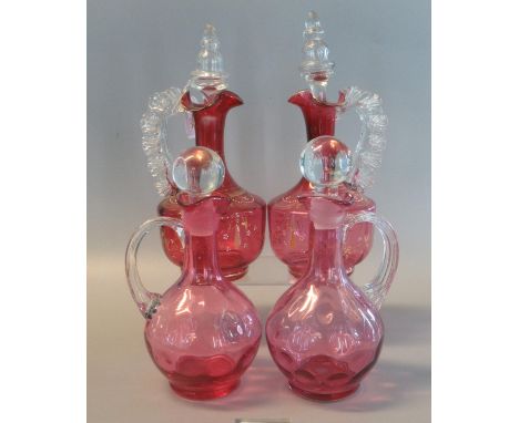 Pair of Victorian cranberry glass baluster-shaped single handled decanters with stoppers, together with another pair of Victo