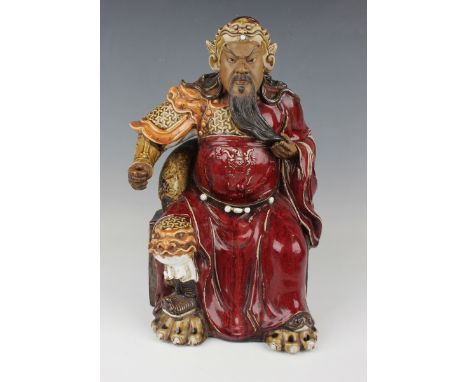 A Chinese Shiwan pottery sang-de-boeuf glazed figure of Guan Yu, mid-20th century, modelled seated wearing a dragon robe, imp