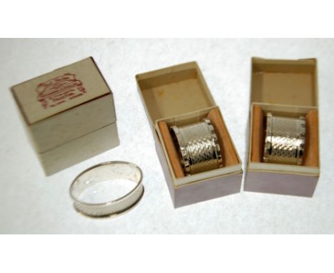 THREE INDIVIDUALLY BOXED GEORGE V ENGINE TURNED SILVER NAPKIN RINGS, comprising; a  PAIR  with castellated borders, Chester 1